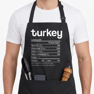 Turkey christmas apron - White nutrition facts label with 18 lines of text showing calories, fat, and protein data — shown on a black cotton canvas apron against a white background