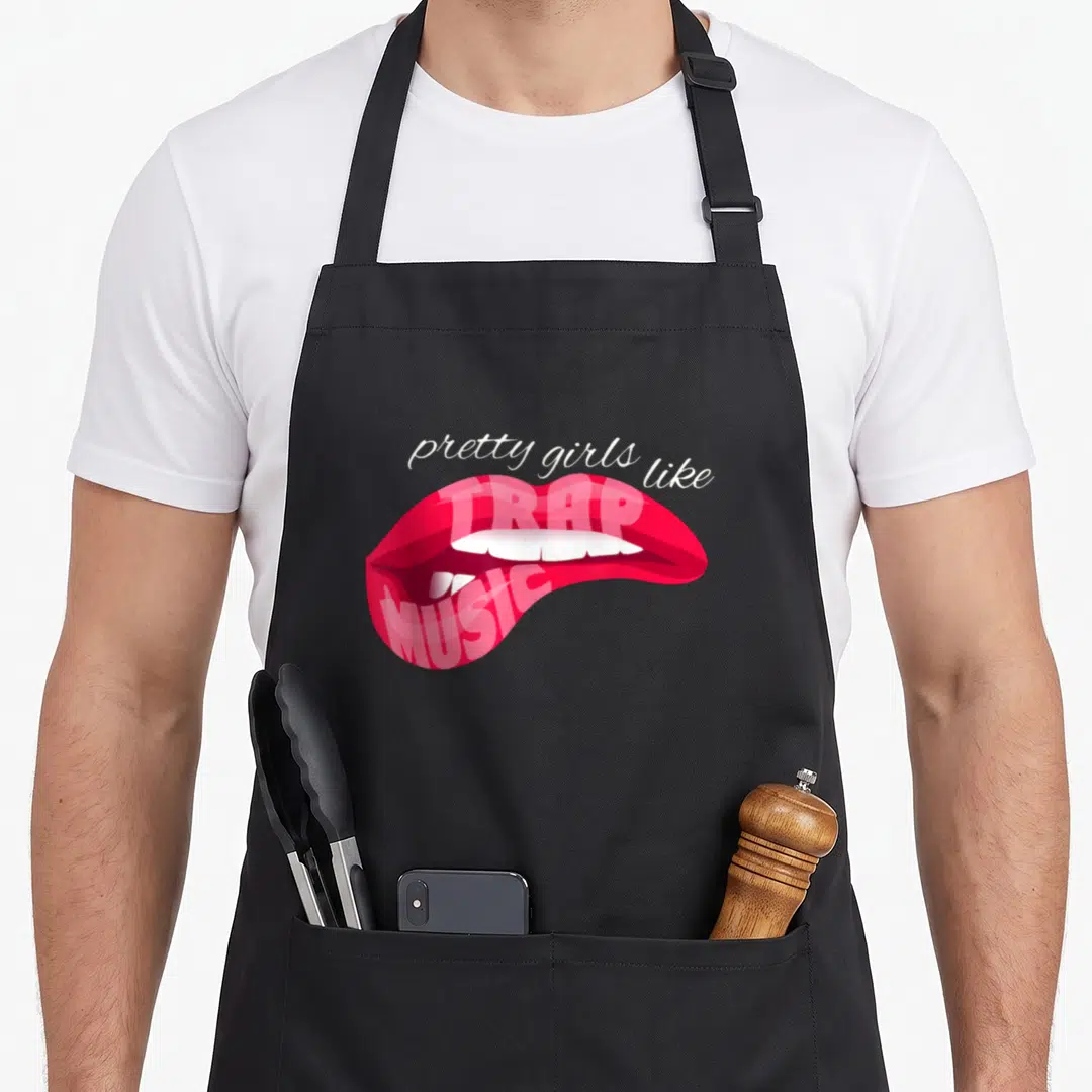 Techno hip apron - Arched white text above open red lips with pink TRAP MUSIC lettering inside — shown on a black cotton canvas apron against a white background