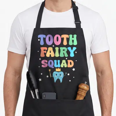 Squad dentist apron - Cartoon blue tooth with crown and wand below stacked TOOTH FAIRY SQUAD text in rainbow colors — shown on a black cotton canvas apron against a white background