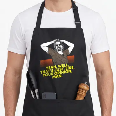 Well yeah apron - Cartoon man holding head above orange lines and yellow quote text — shown on a black cotton canvas apron against a white background