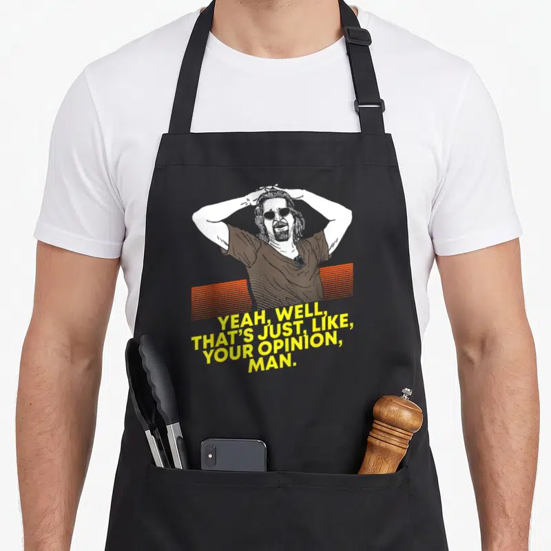 Well yeah apron - Cartoon man holding head above orange lines and yellow quote text — shown on a black cotton canvas apron against a white background