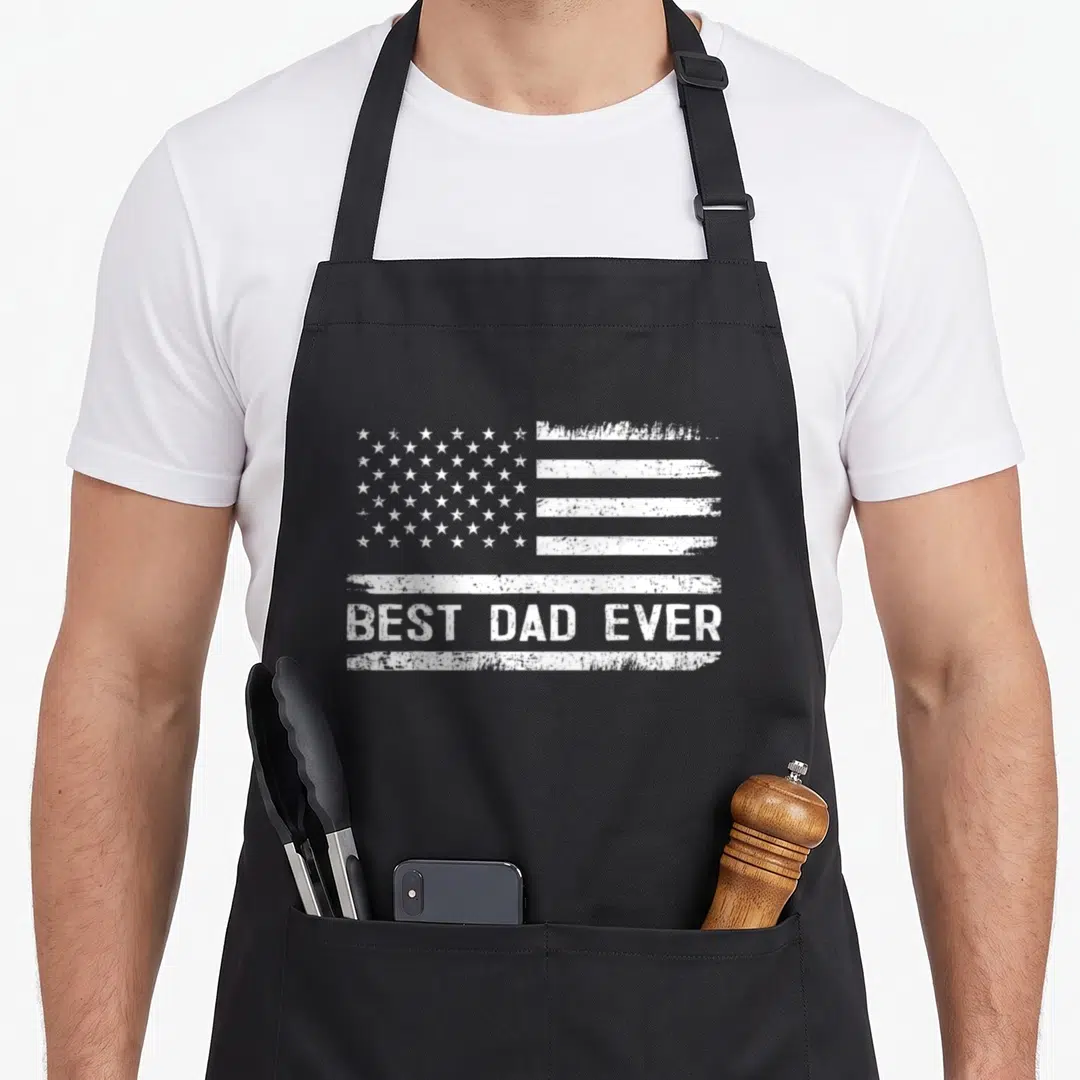 Funny father american flag apron - Distressed white American flag above BEST DAD EVER text in monochrome print — shown on a black cotton canvas apron against a white background