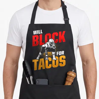 Taco football apron - Distressed football player blocking red block orange tacos text — shown on a black cotton canvas apron against a white background