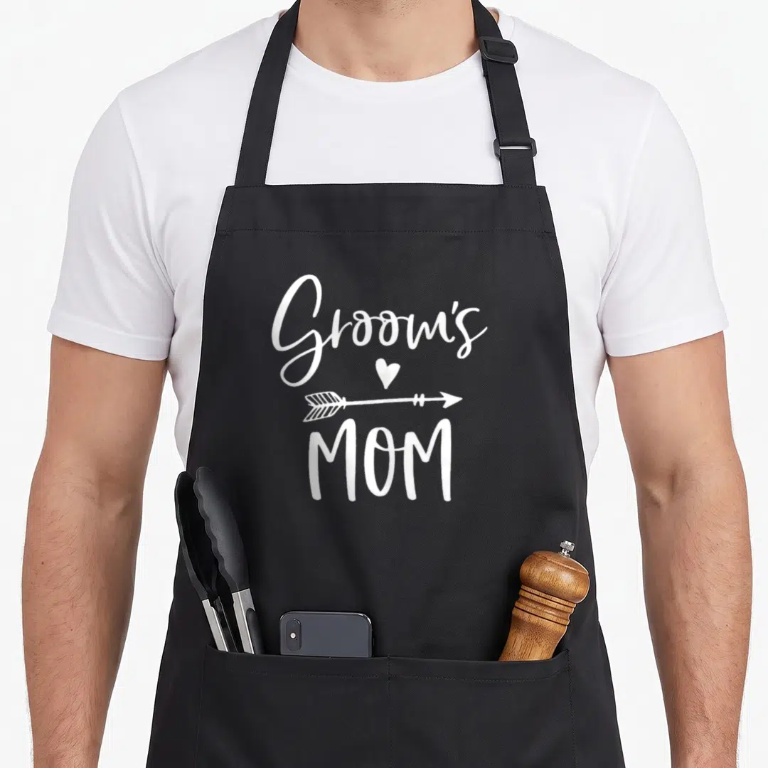 Groom force mom apron - White Groom's MOM text with heart and arrow stacked vertically — shown on a black cotton canvas apron against a white background