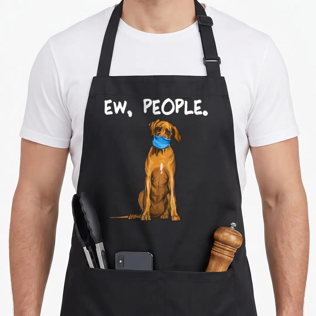 Rhodesian dog face apron - Cartoon brown dog in blue mask with ew people text above — shown on a black cotton canvas apron against a white background