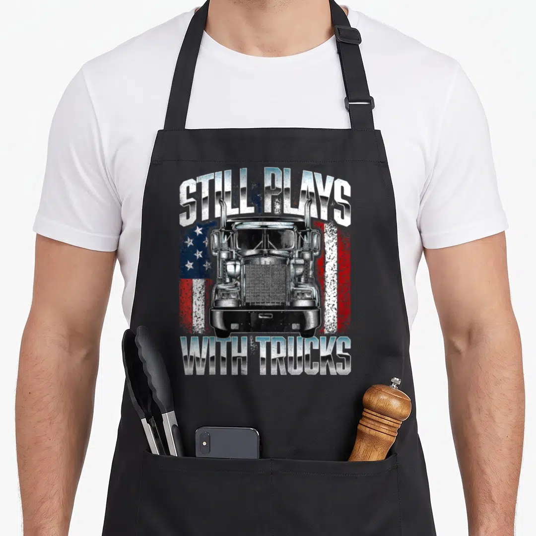 Play driver semi truck apron - Realistic truck front view on distressed American flag with arched text still plays — shown on a black cotton canvas apron against a white background