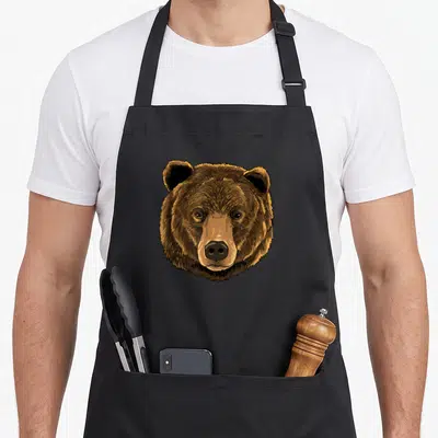 Wild bear apron - Realistic brown and black illustration of a grizzly bear head facing forward — shown on a black cotton canvas apron against a white background