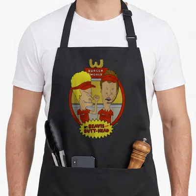 Beavis burger apron - Two cartoon characters in red oval with BURGER WORLD text and yellow starburst logo — shown on a black cotton canvas apron against a white background