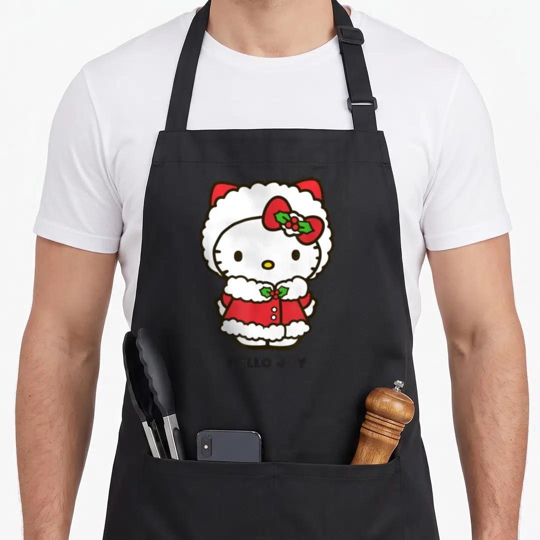 Funny joy holiday apron - Hello Kitty in red Santa suit with holly and HELLO JOY text — shown on a black cotton canvas apron against a white background