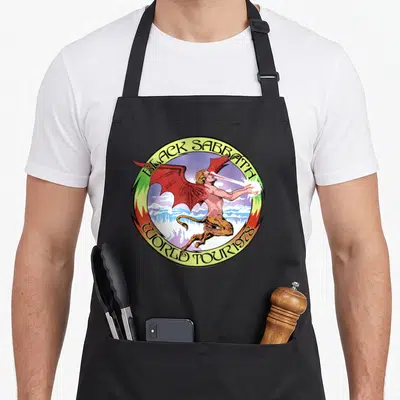 Tour black officially apron - Demon with red wings inside yellow circle reading BLACK SABBATH WORLD TOUR 1978 — shown on a black cotton canvas apron against a white background
