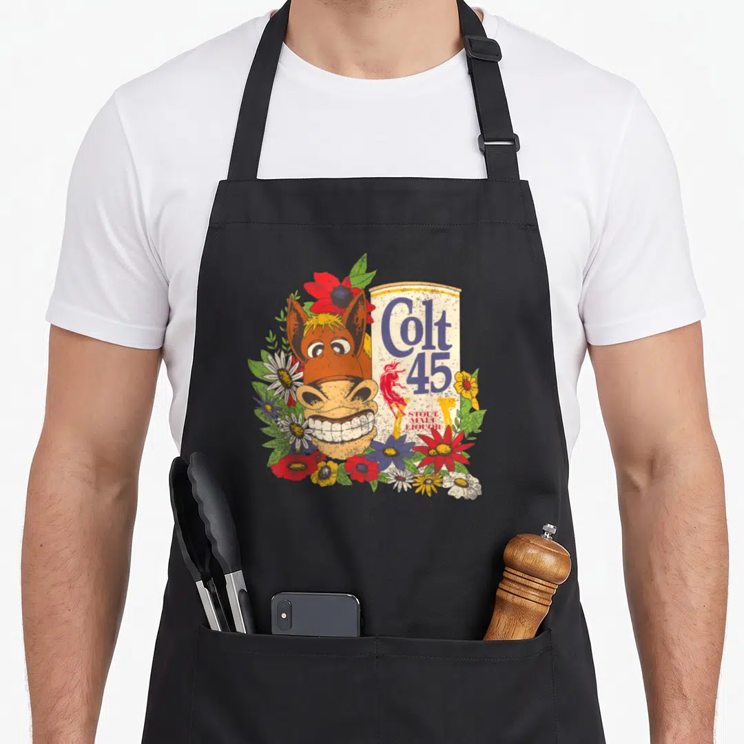 Colt beer apron - Cartoon horse head grinning next to Colt 45 can surrounded by red blue and yellow flowers — shown on a black cotton canvas apron against a white background