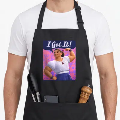Luisa floral apron - Strong woman flexing arm under I Got It text on pink purple floral background — shown on a black cotton canvas apron against a white background