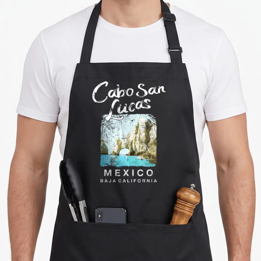 Travel mexico apron - Cabo San Lucas rock arch photo with white text and turquoise water on black bib — shown on a black cotton canvas apron against a white background