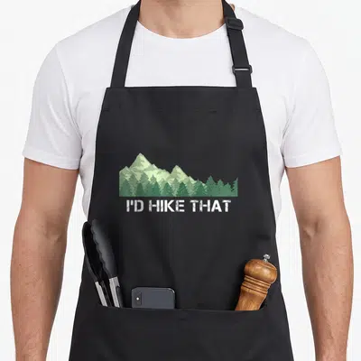 Hike camping apron - Green mountain landscape with white text reading I'D HIKE THAT — shown on a black cotton canvas apron against a white background