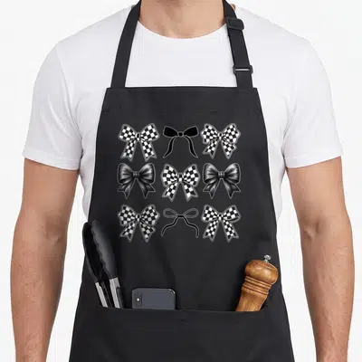 Bow car apron - Nine black and white bows in 3x3 grid including checkered and satin styles — shown on a black cotton canvas apron against a white background