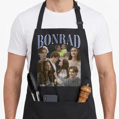 Bonrad pretty apron - Arched BONRAD text above photo collage of a man and woman in blue grey and white tones on a black — shown on a black cotton canvas apron against a white background