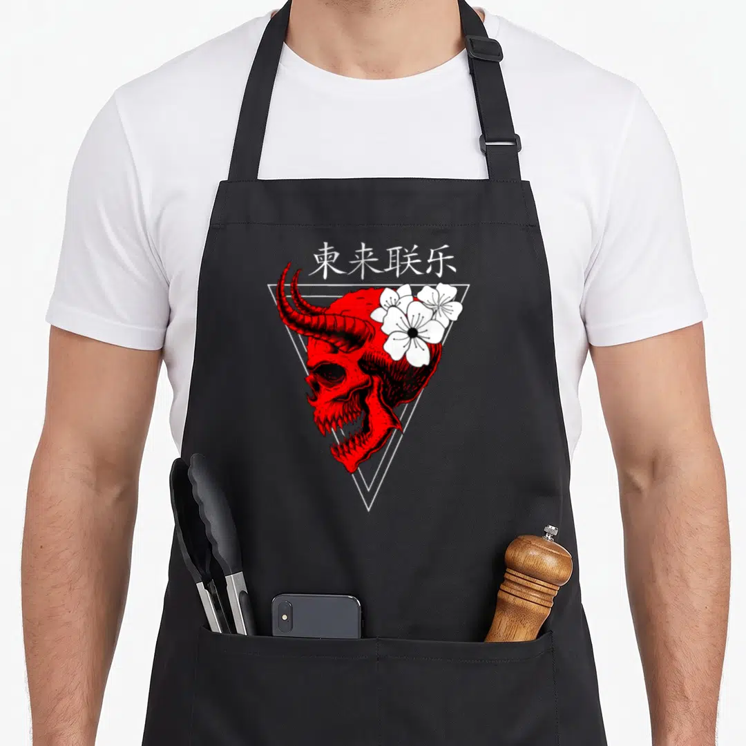 Japanese vaporwave apron - Red horned demon skull with white flowers inside white triangle frame topped with Chinese — shown on a black cotton canvas apron against a white background