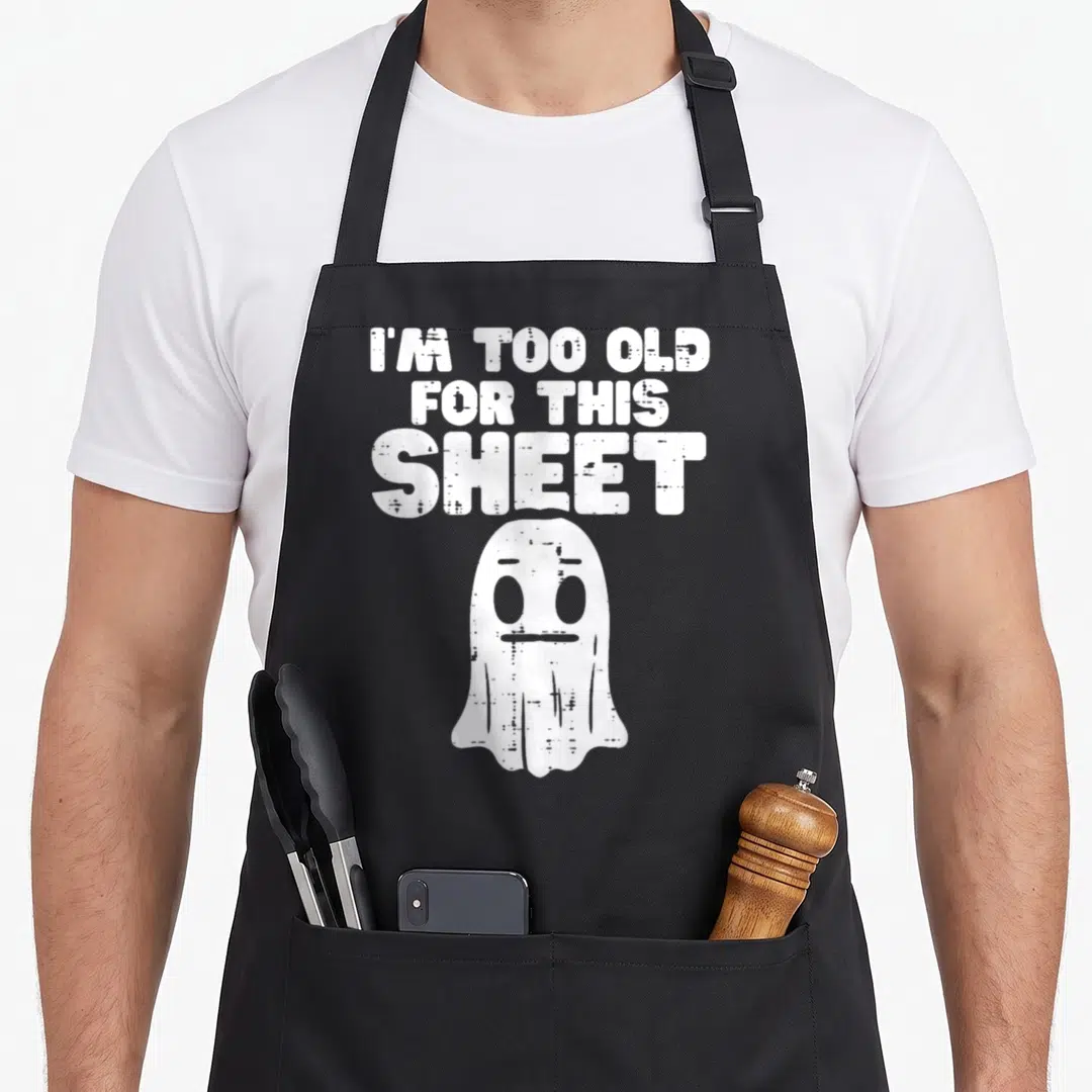 Ghost costume halloween apron - White distressed ghost below stacked text reading I'M TOO OLD FOR THIS SHEET — shown on a black cotton canvas apron against a white background