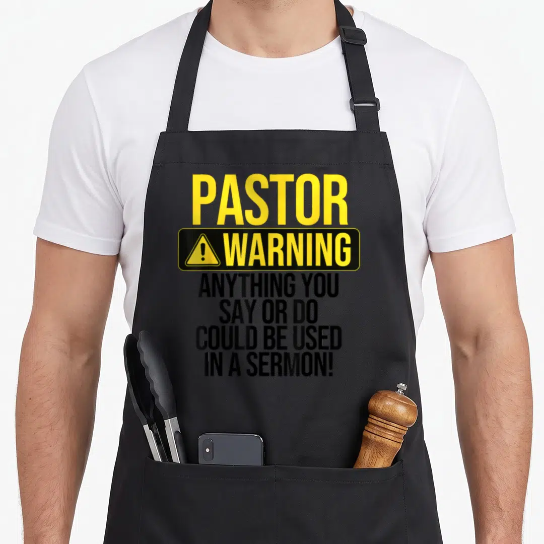 Pastor religious aprons - Yellow and black warning sign typography reading Pastor Warning Anything You Say Or Do Could — shown on a black cotton canvas apron against a white background