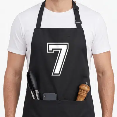 Jersey sports team aprons - White outlined number 7 in varsity block font on black fabric — shown on a black cotton canvas apron against a white background