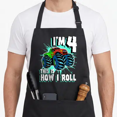 Birthday 4th truck apron - Monster truck graphic with text I'M 4 THIS IS HOW I ROLL in red blue and green — shown on a black cotton canvas apron against a white background