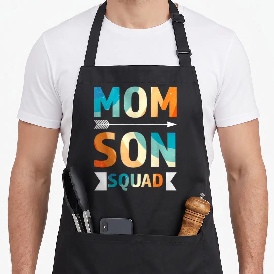 Son my mother's apron - Stacked MOM SON text with white arrow and SQUAD banner in teal cream orange white — shown on a black cotton canvas apron against a white background