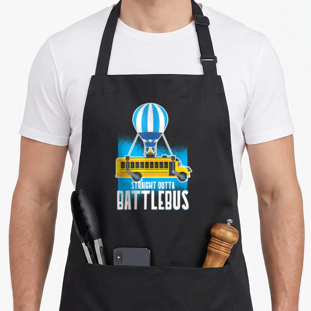 Straight battle royale apron - Yellow bus with wheel cannons suspended by blue white striped balloon with white text — shown on a black cotton canvas apron against a white background