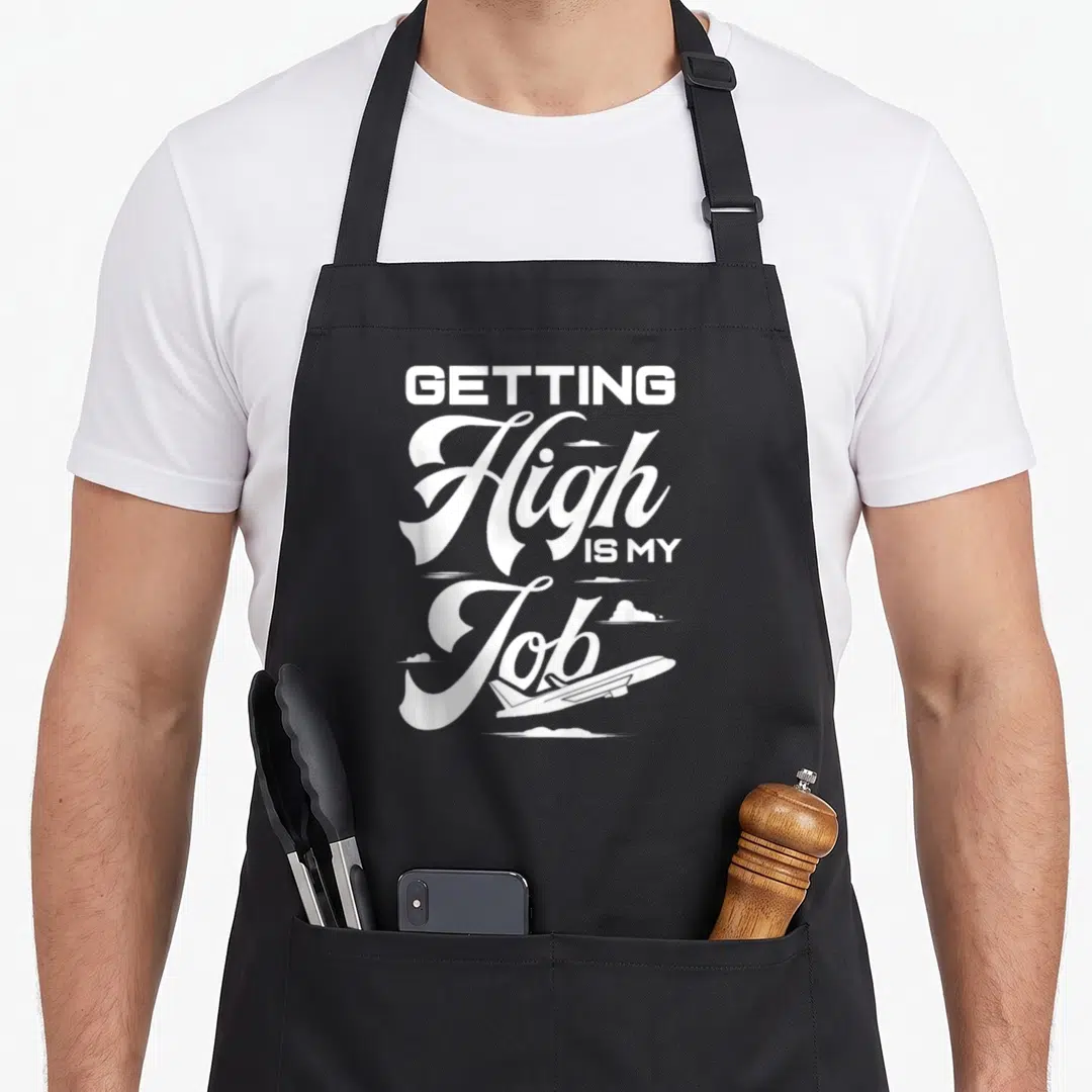 Pilot flight attendant apron - White stacked text Getting High Is My Job above airplane and clouds — shown on a black cotton canvas apron against a white background