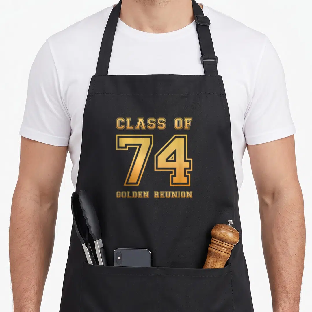 Class golden apron - CLASS OF 74 GOLDEN REUNION text in gold and orange varsity font — shown on a black cotton canvas apron against a white background