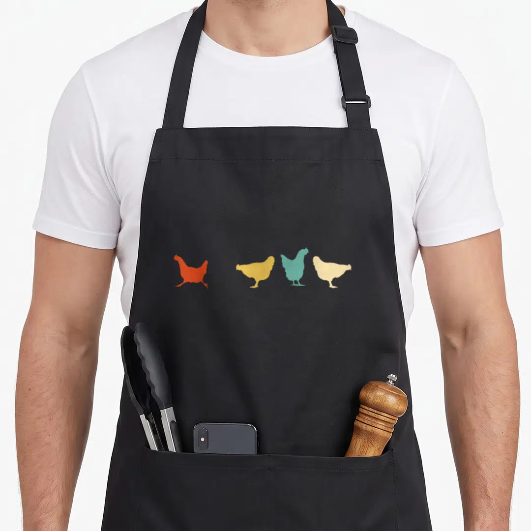 Chicken custom pet apron - Four chicken silhouettes in orange, yellow, teal, and beige arranged horizontally — shown on a black cotton canvas apron against a white background