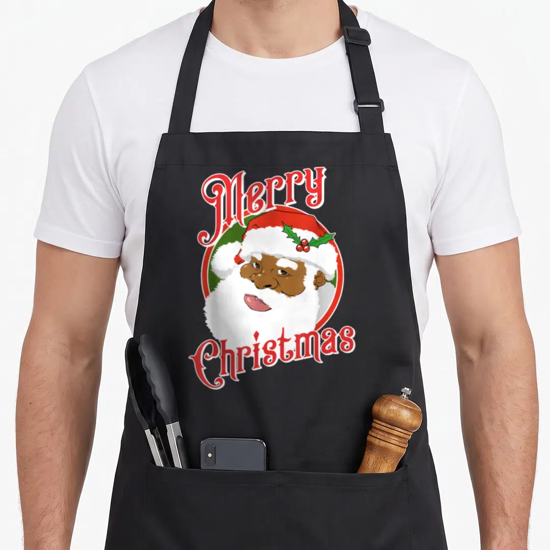 Merry santa claus apron - Cartoon Santa face with holly hat inside red and green circle with arched Merry Christmas text — shown on a black cotton canvas apron against a white background