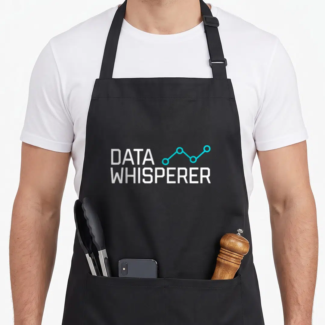 Whisperer science apron - DATA WHISPERER text with cyan line graph and dots on white background — shown on a black cotton canvas apron against a white background