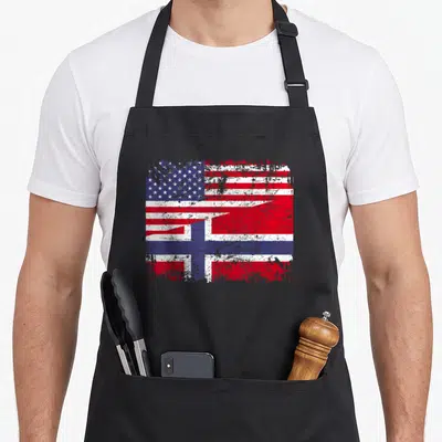 Root norwegian kitchen aprons - Merged USA and Norway flags with distressed texture in red, white, and blue colors — shown on a black cotton canvas apron against a white background