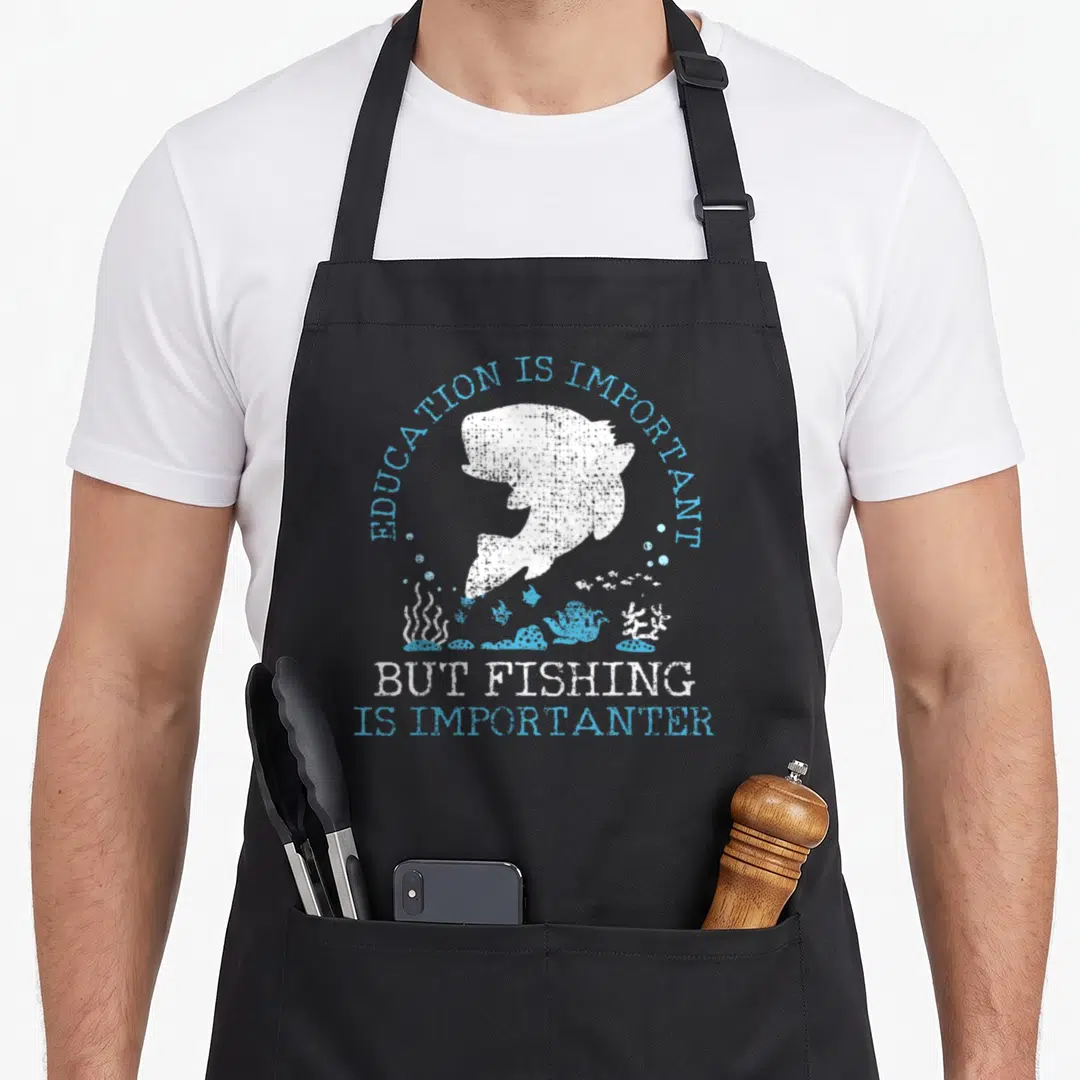 Fishing education apron - White fish silhouette under arched blue text with underwater plants and bubbles in distressed — shown on a black cotton canvas apron against a white background