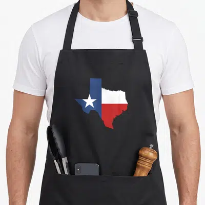 Star texas apron - Texas state map outline filled with blue, white, and red flag colors — shown on a black cotton canvas apron against a white background