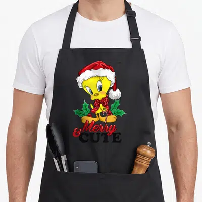 Tweety merry christmas apron - Yellow cartoon bird in red hat holding candy cane with holly leaves and text below — shown on a black cotton canvas apron against a white background