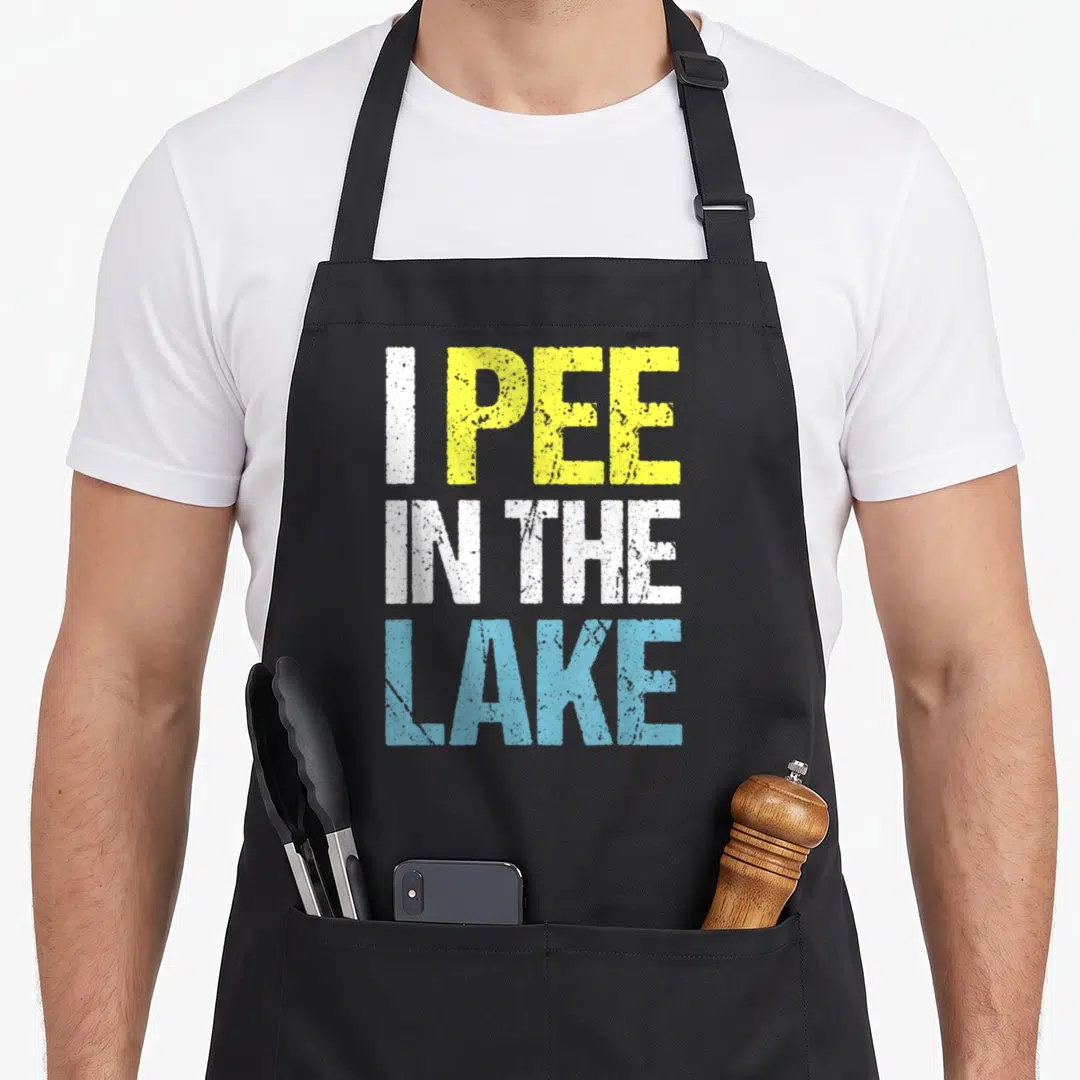 Pee summer aprons - Stacked text reading I PEE IN THE LAKE in yellow white and light blue — shown on a black cotton canvas apron against a white background