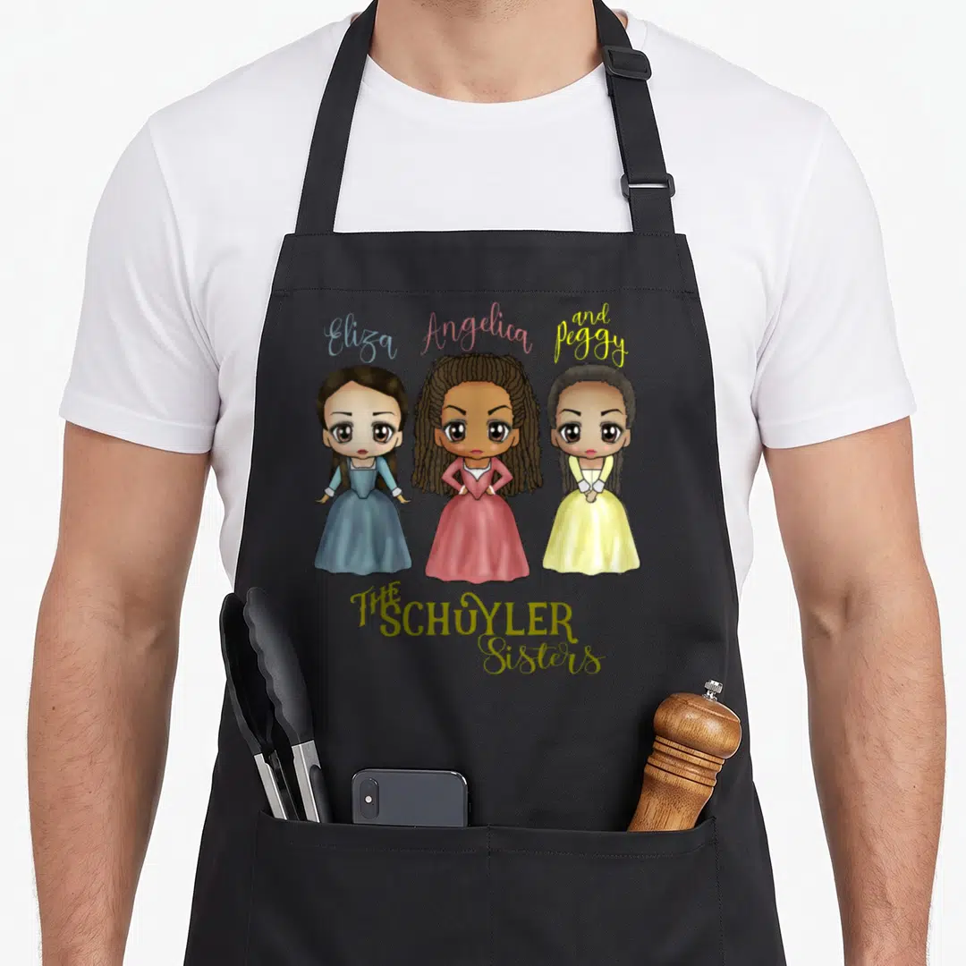 Sister kawaii apron - Three cartoon women in blue pink yellow dresses with names Eliza Angelica Peggy and THE SCHUYLER — shown on a black cotton canvas apron against a white background