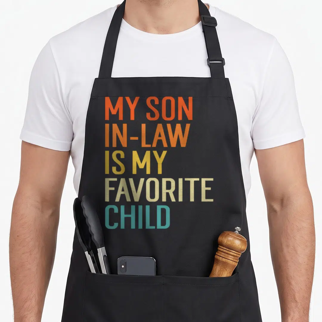 Son family aprons - Stacked text reading My Son In-Law Is My Favorite Child in orange yellow beige and teal — shown on a black cotton canvas apron against a white background
