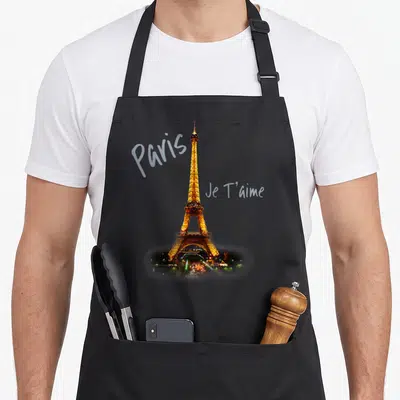 Tower paris apron - Illuminated Eiffel Tower photo with Paris and Je T'aime text in grey script — shown on a black cotton canvas apron against a white background