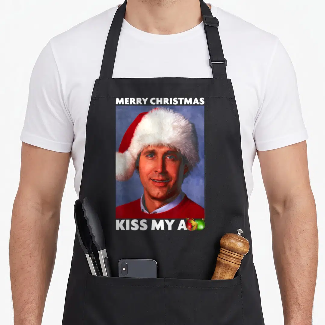 Vacation merry christmas apron - Man in Santa hat with Merry Christmas text and ornaments replacing final letter — shown on a black cotton canvas apron against a white background