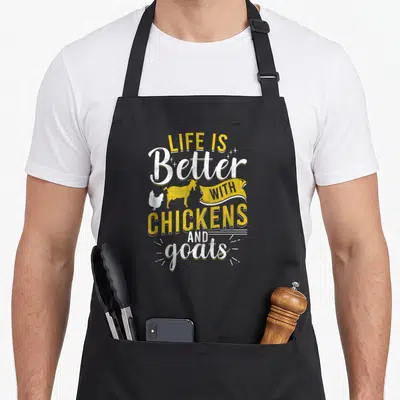 Goat chicken apron - LIFE IS Better WITH CHICKENS AND goats text with goat and chicken silhouettes in yellow and white — shown on a black cotton canvas apron against a white background