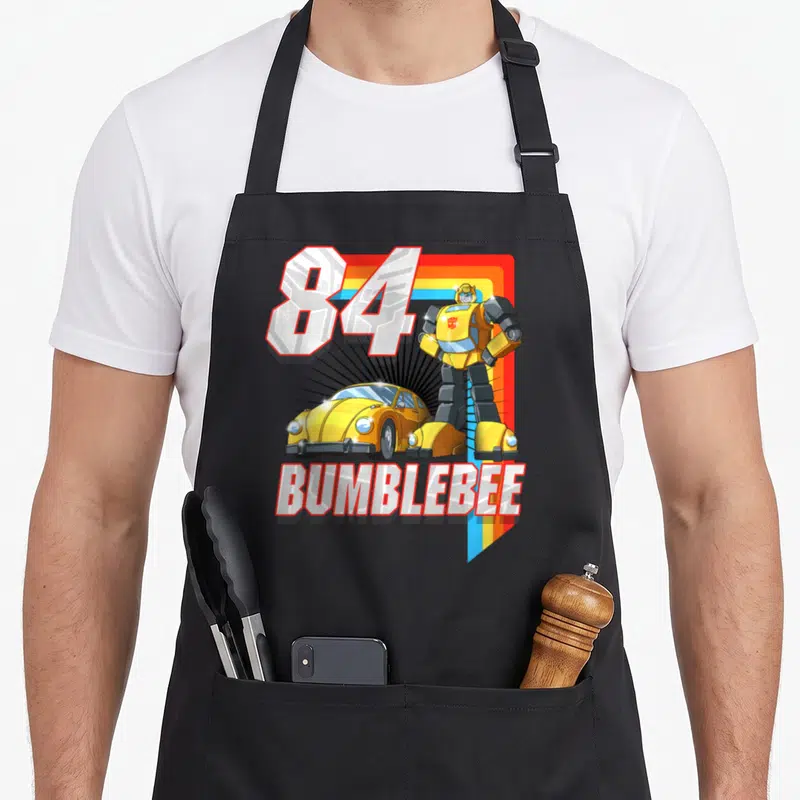 Bumblebee stripe apron - 84 Bumblebee robot yellow car cartoon print with rainbow stripe — shown on a black cotton canvas apron against a white background