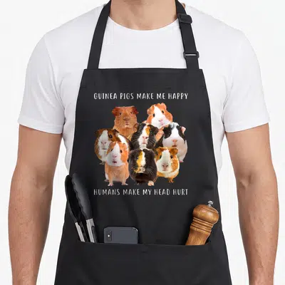 Pig guinea lover apron - Cluster of white brown and black guinea pigs between two lines of white text on grey background — shown on a black cotton canvas apron against a white background