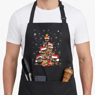 Yorkie christmas tree apron - Nine Yorkshire Terriers stacked in a pyramid wearing Santa hats with a gold star — shown on a black cotton canvas apron against a white background