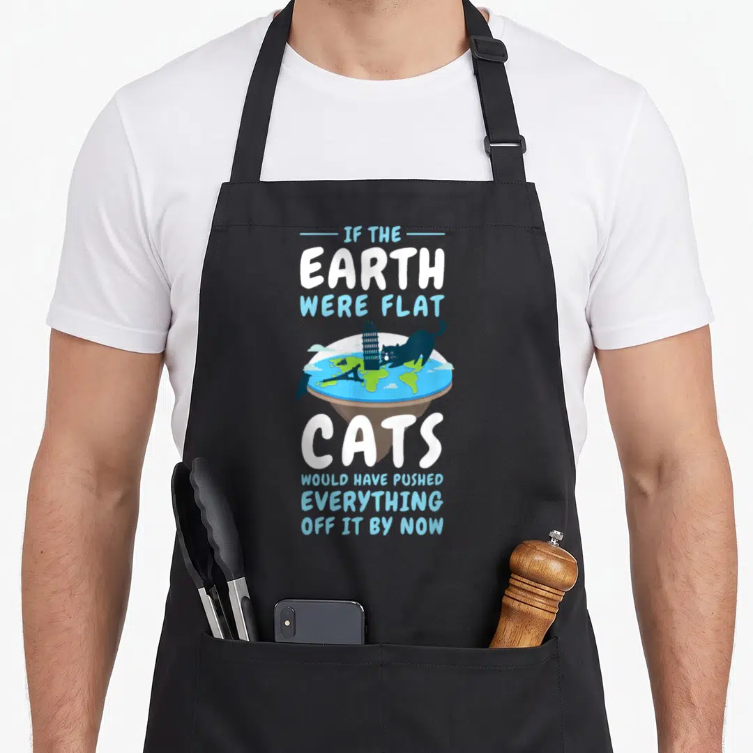 Round cat apron - Cat pushing Leaning Tower off flat earth disc with sarcastic text — shown on a black cotton canvas apron against a white background
