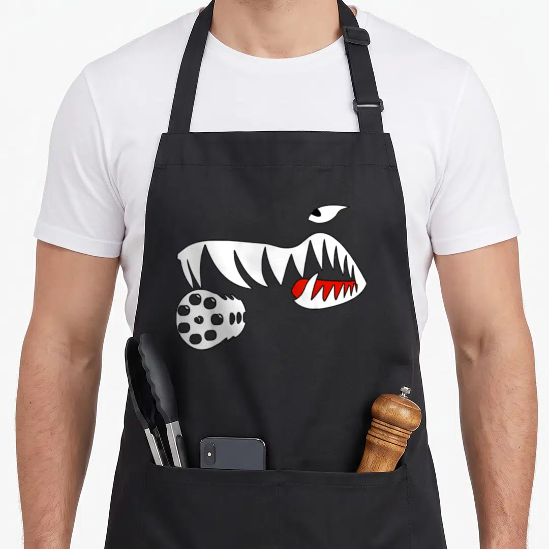 Hog vet apron - Cartoon monster mouth with sharp teeth, red tongue, and perforated gatling gun bone in white red — shown on a black cotton canvas apron against a white background