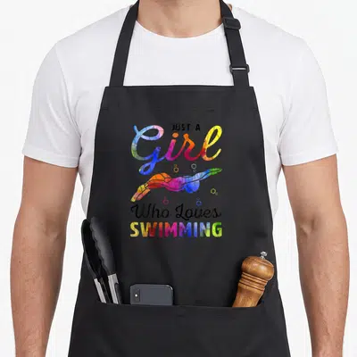 Swimming swimmer apron - Just A Girl Who Loves Swimming text with watercolor swimmer and bubbles in blue pink yellow — shown on a black cotton canvas apron against a white background