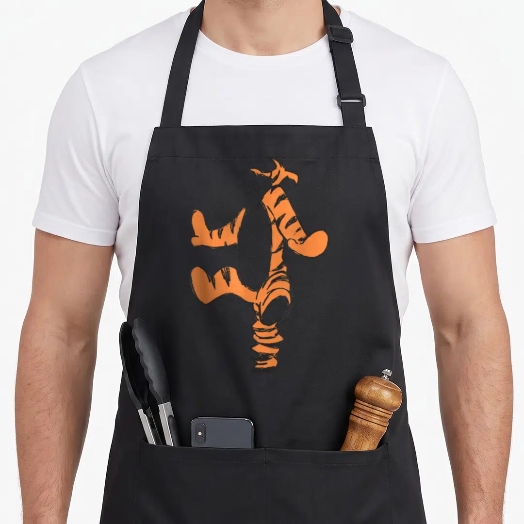 Sketch simple apron - Orange and black tiger sketch in a cartoon style with bouncy posture — shown on a black cotton canvas apron against a white background