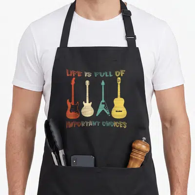 Electric guitar acoustics apron - Four colorful guitars in red beige teal and yellow with text LIFE IS FULL — shown on a black cotton canvas apron against a white background